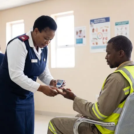 A nurse taking a finger-prick glucose reading